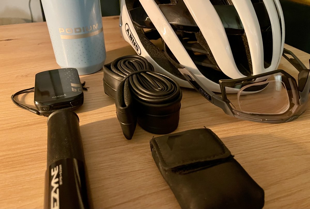 Rzeczy przygotowane do zabrania na rower: bidon, multitool, licznik rowerowy, kask, okulary, zapasowa dętka, pompka rowerowa